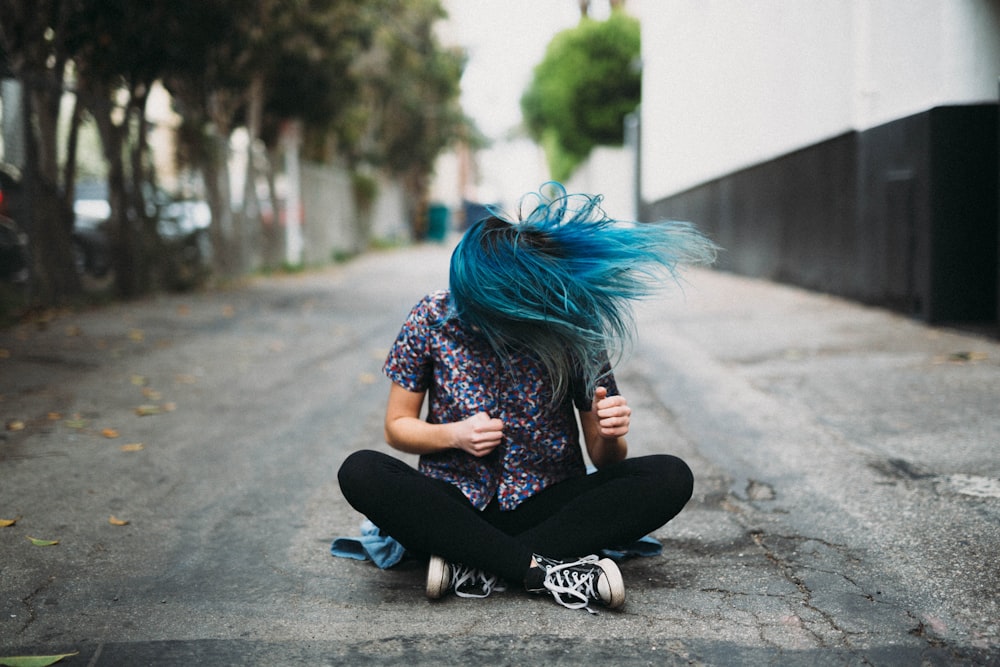 woman sitting on ground beside buildings