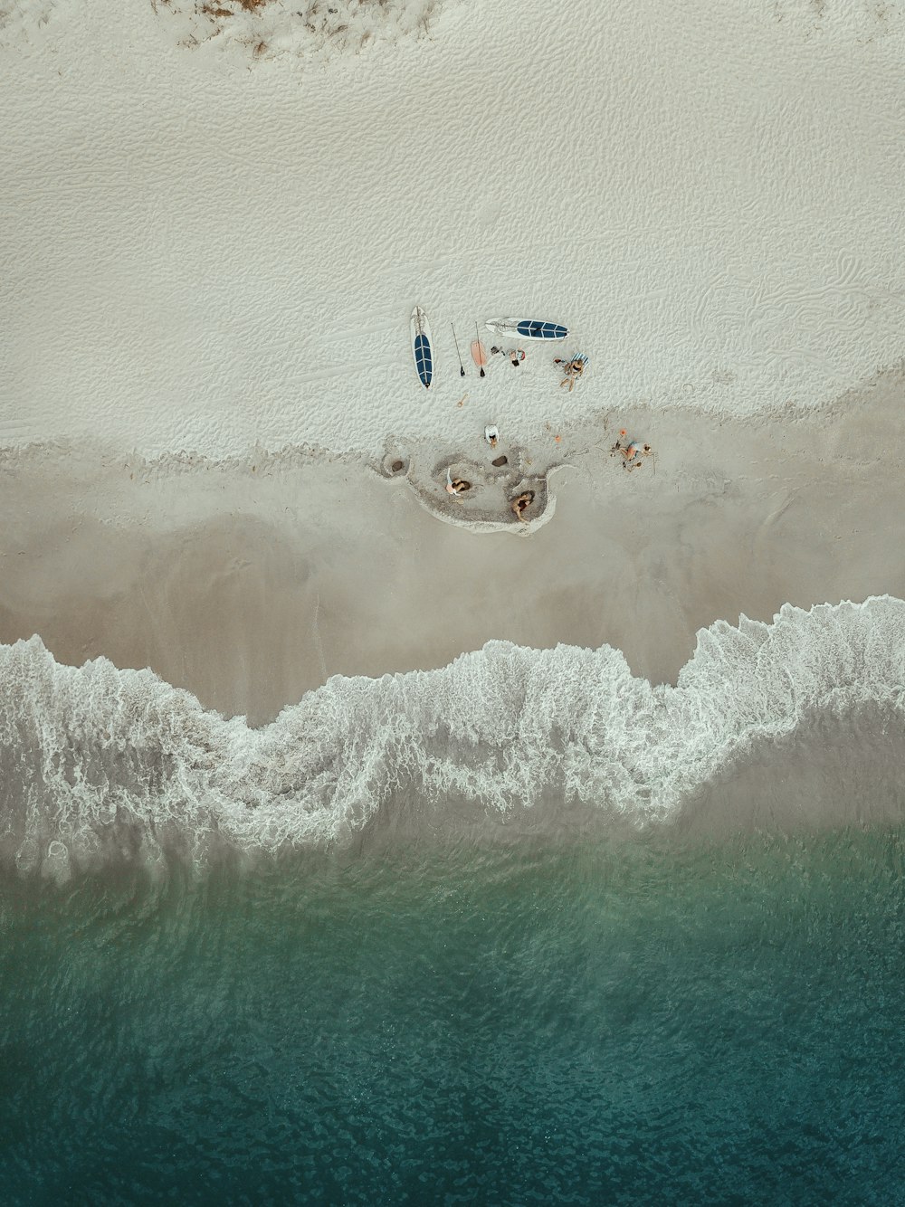 昼間、カヤック近くの海岸に横たわる人々の航空写真