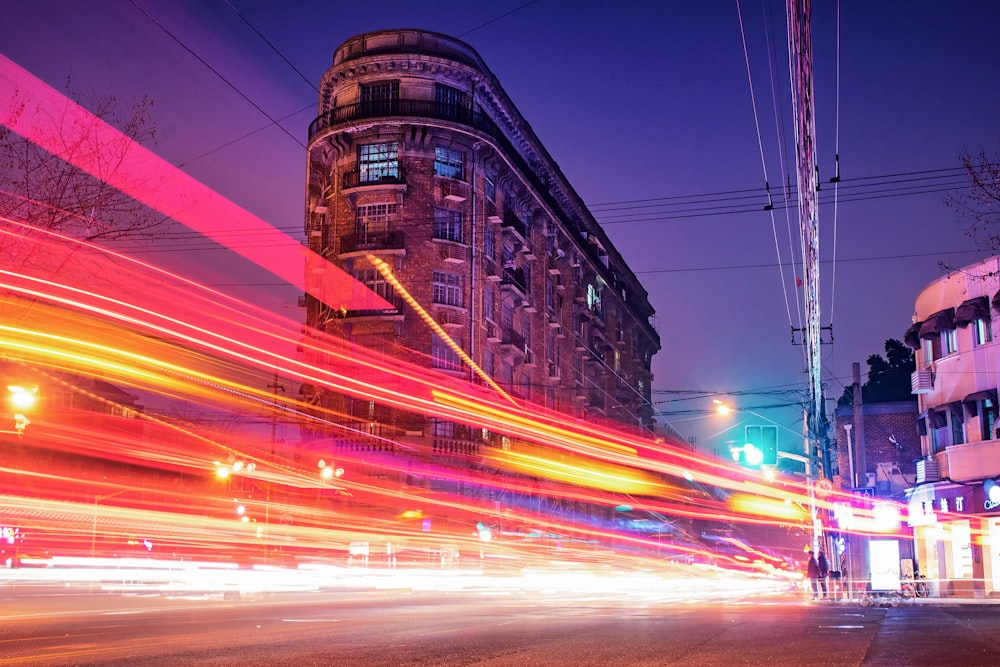 time-lapse photography of cars passing through the road between buildings during night time