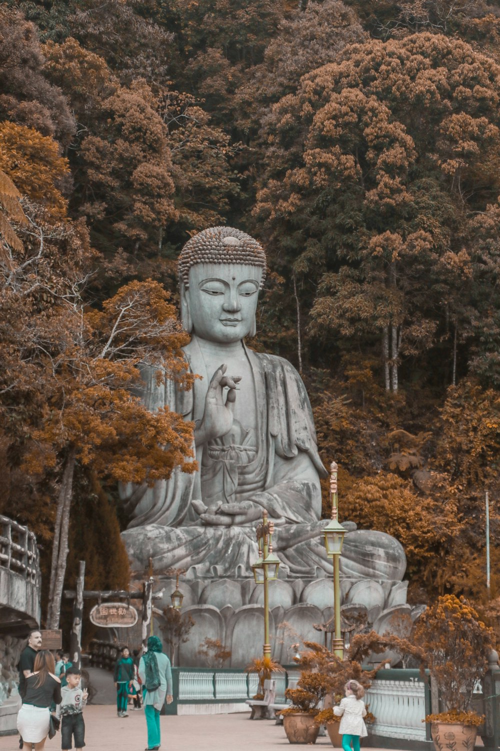 Menschen, die tagsüber in der Nähe der Buddha-Statue in der Nähe von Bäumen spazieren gehen