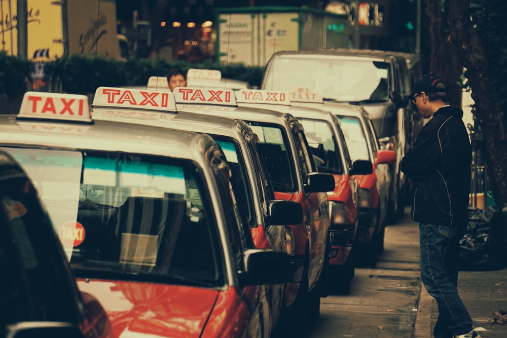 person standing near parked taxi during daytime