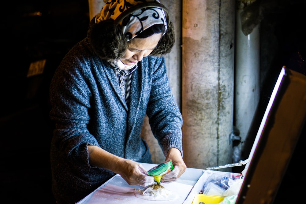 woman wearing blue knit jacket holding green labeled pack