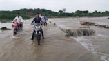 Group of motorcyclists crossing a shallow river during a guided ride.