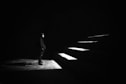 grayscale photo of man standing in front of stairs