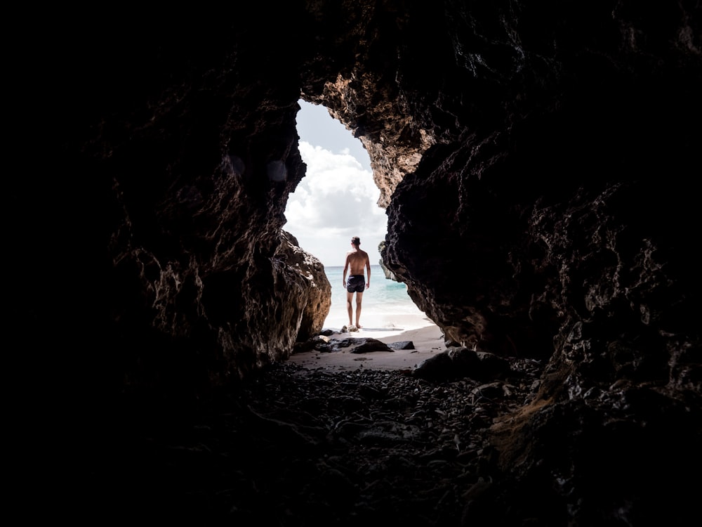 man standing in front of cave