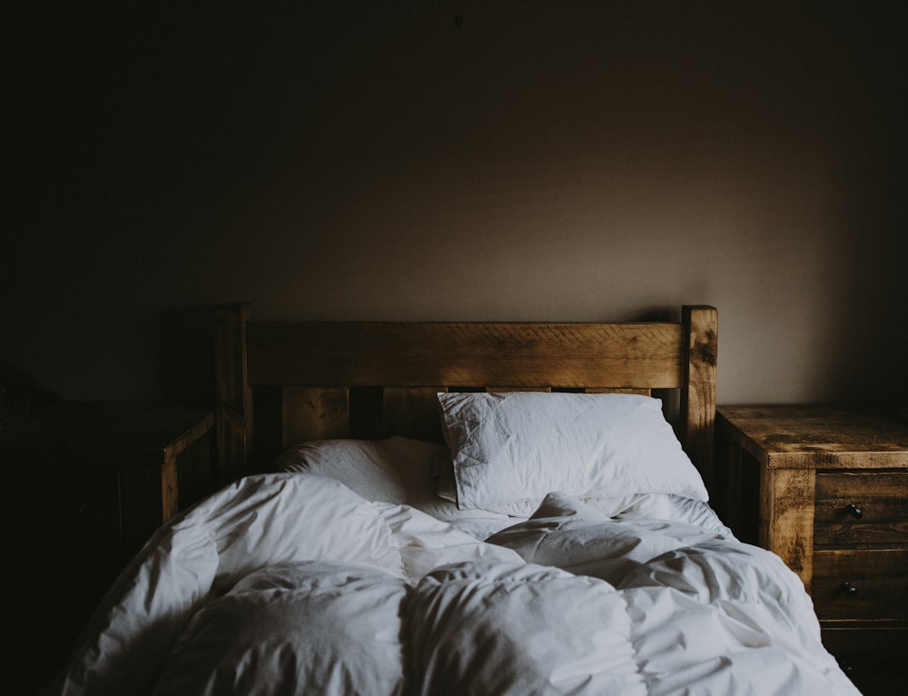 set di piumino da letto bianco e struttura del letto in legno marrone accanto al comodino in legno marrone