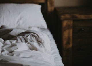 white cushion on bed near brown wooden nightstand