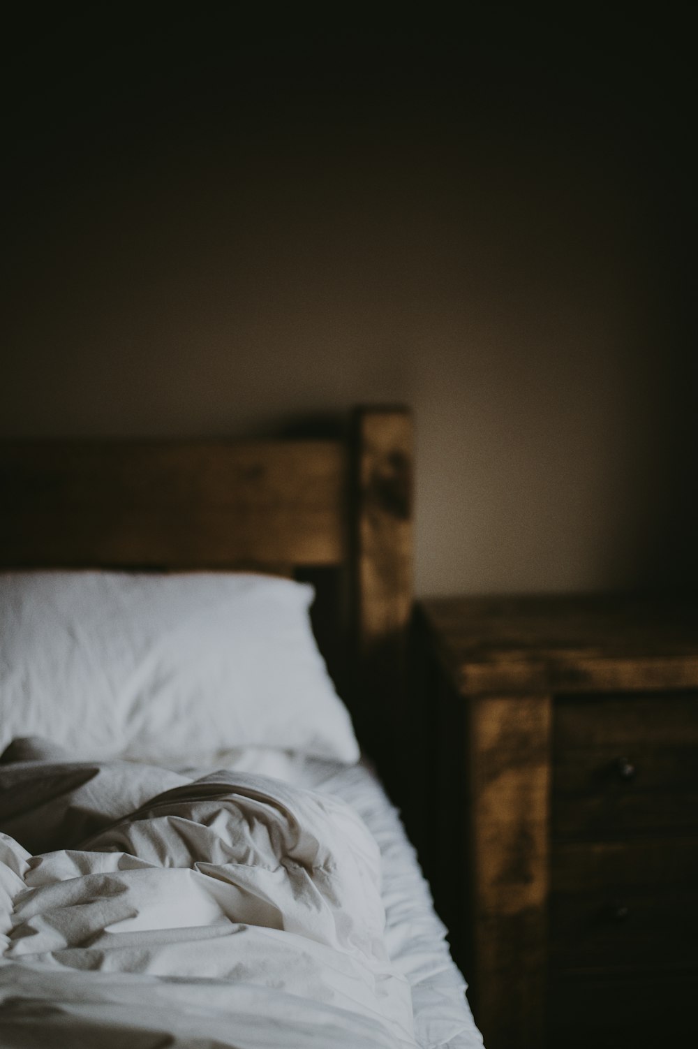 Almofada branca na cama perto da mesa de cabeceira de madeira marrom