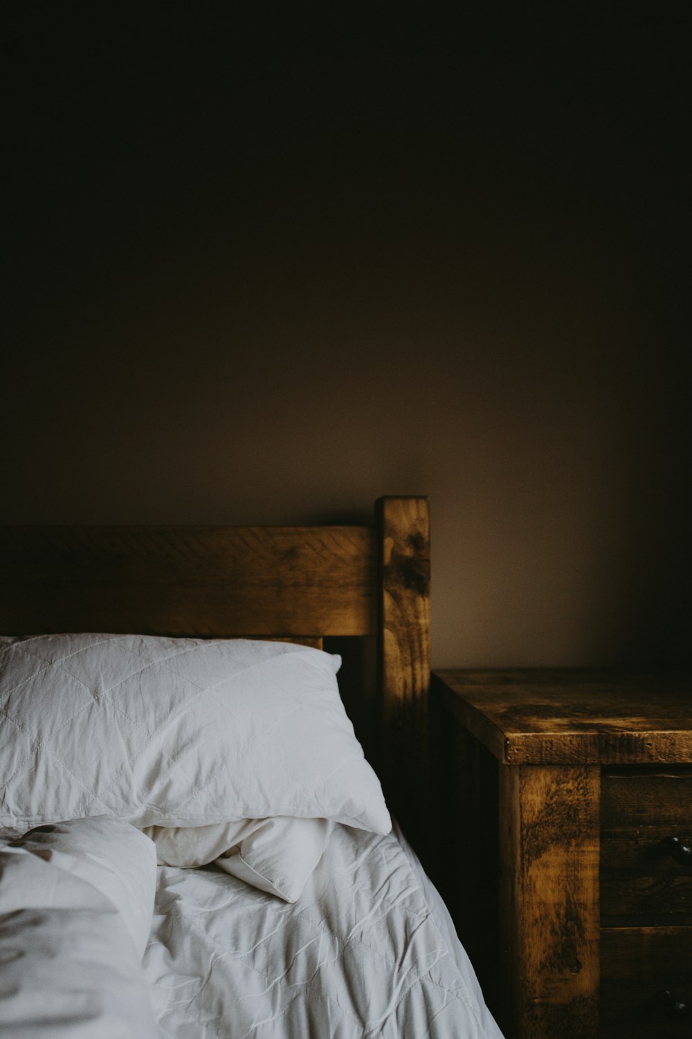 茶色の木製ベッドフレームとナイトテーブル