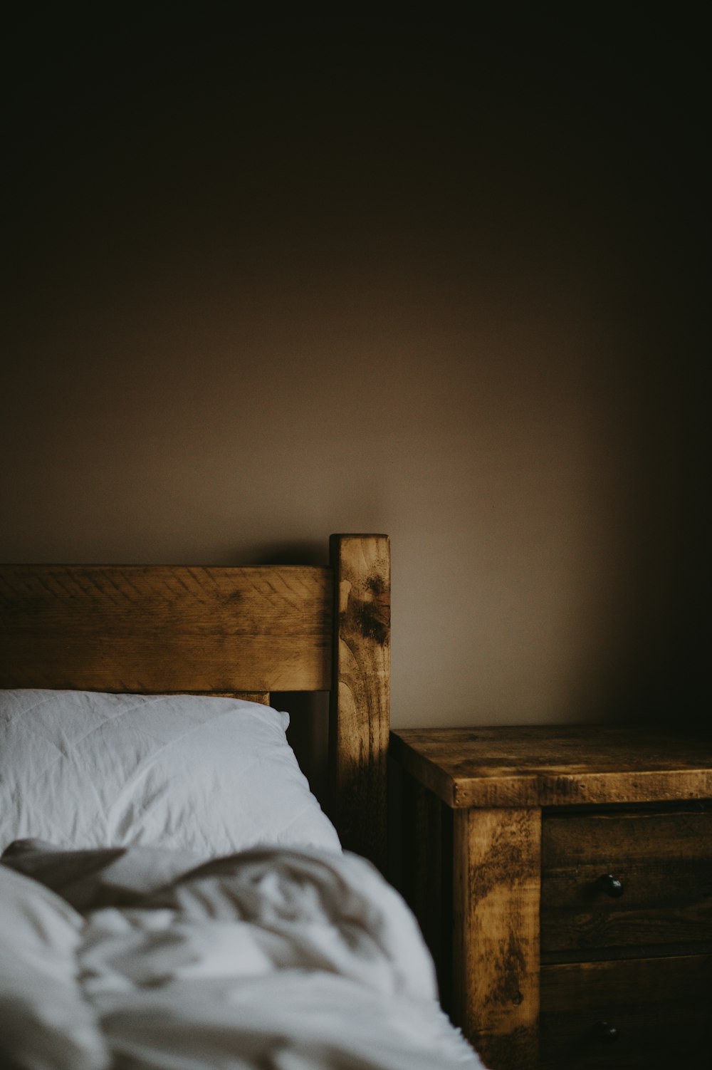 brauner Nachttisch aus Holz neben dem Bett