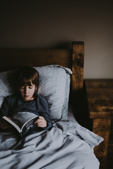 A cozy bedtime scene with a parent reading a storybook to a child under soft lighting.