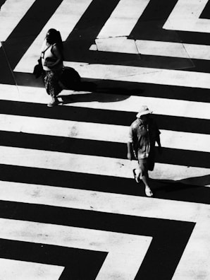 woman and man waling on white and black striped road