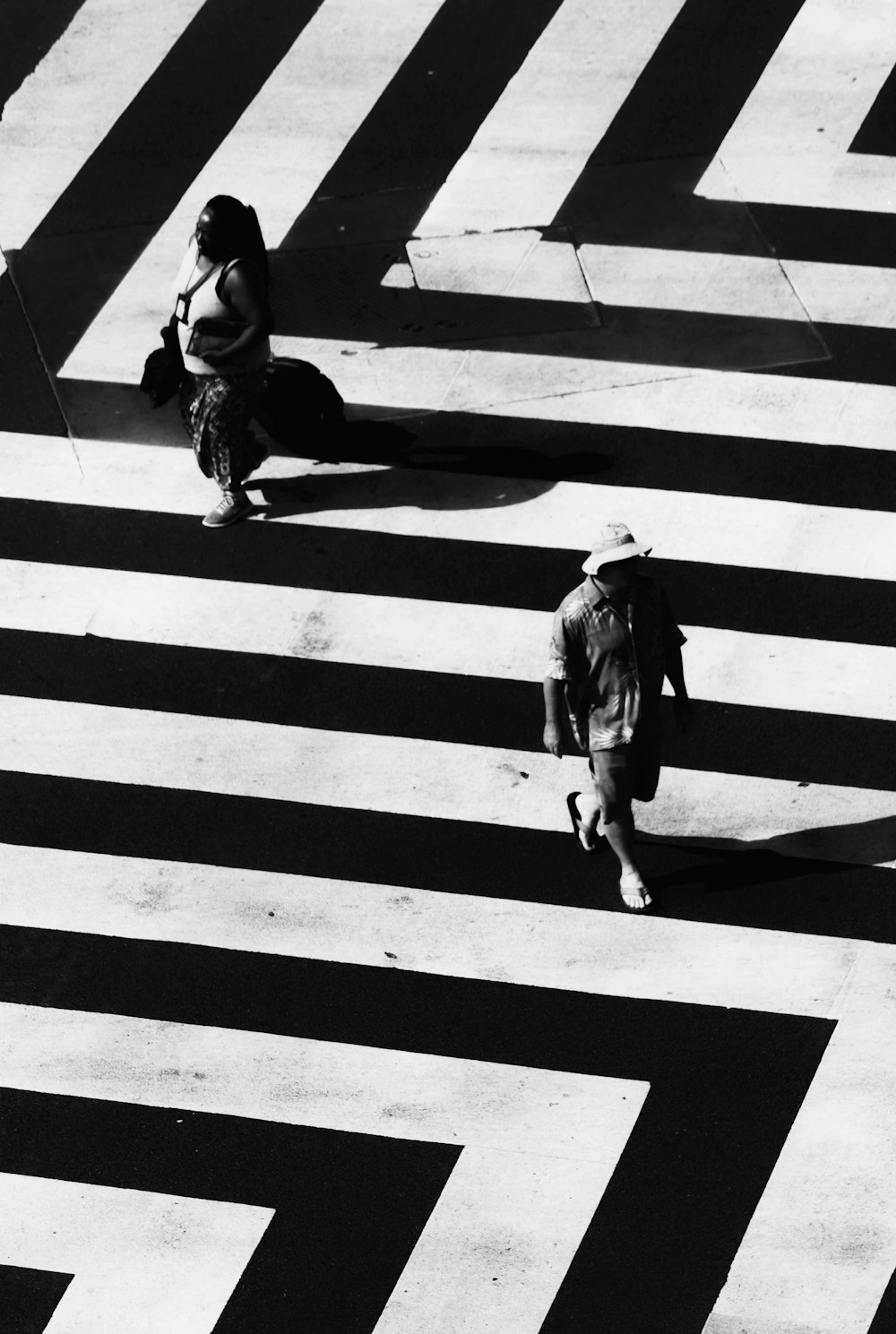 woman and man waling on white and black striped road
