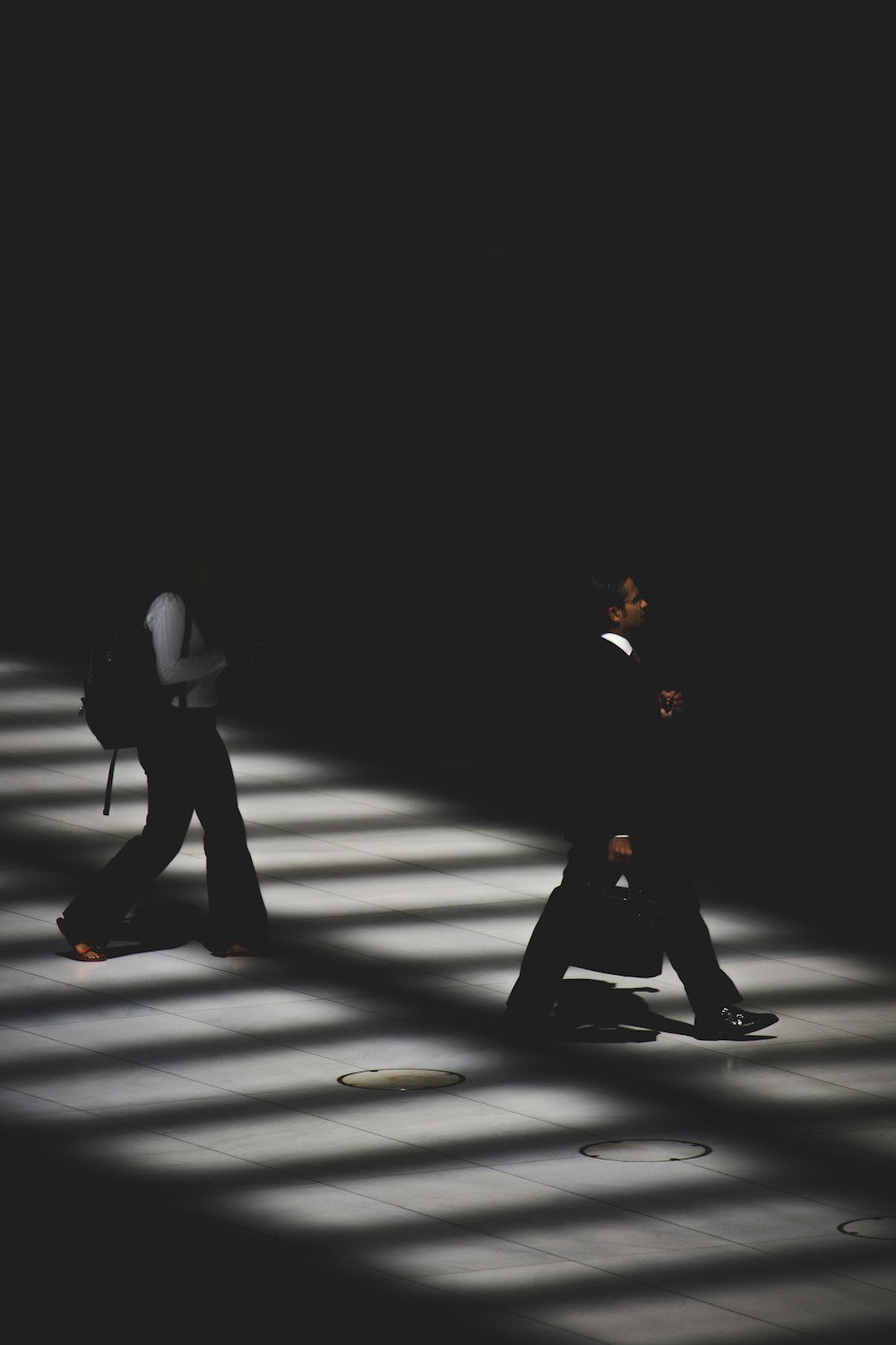 duas pessoas andando dentro do prédio com iluminação preta