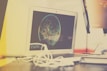 A laptop with an open screen displaying digital artwork, possibly of a planet with abstract design elements. The laptop is placed on a desk cluttered with white cables next to a monitor or another electronic device.