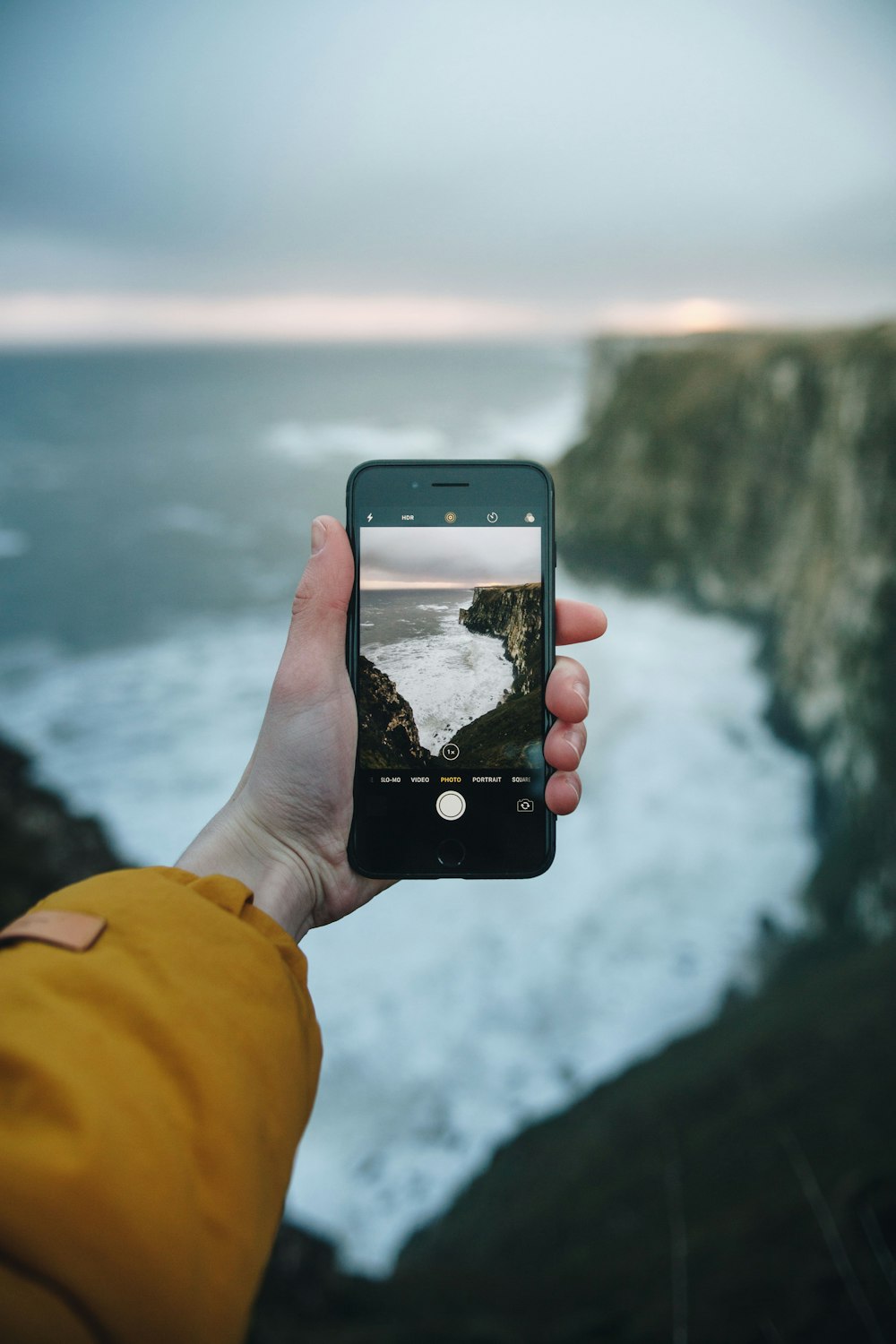 海の波の写真を撮る携帯電話を持っている人