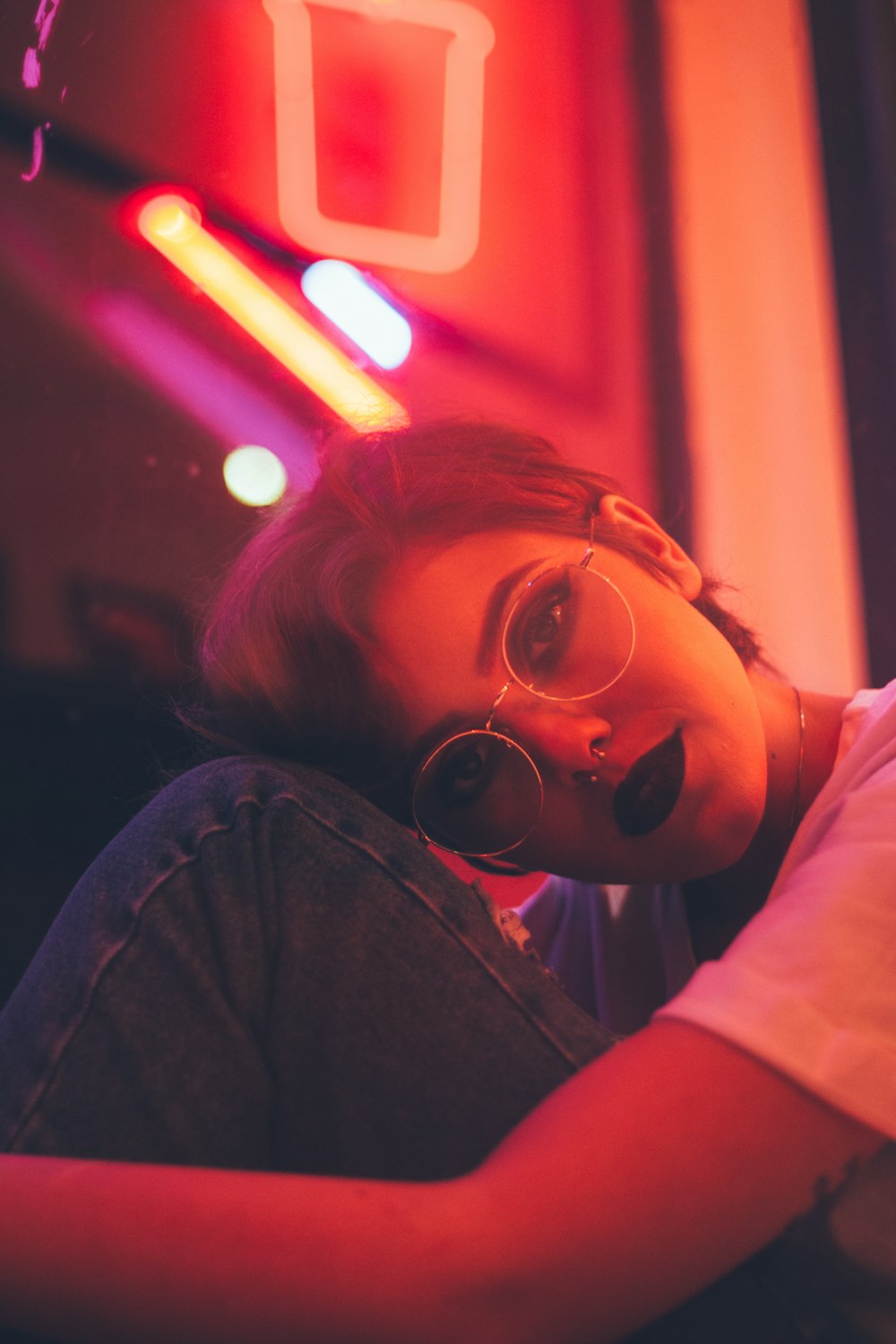 woman leaning on wall with neon light signage