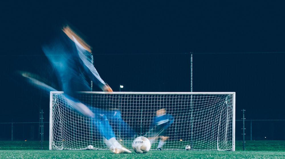 photo timelapse d’un joueur de football frappant dans un ballon