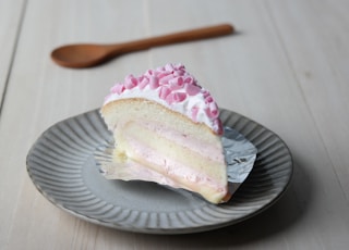 chiffon cake with white icing and pink shredded chocolate on grey plate