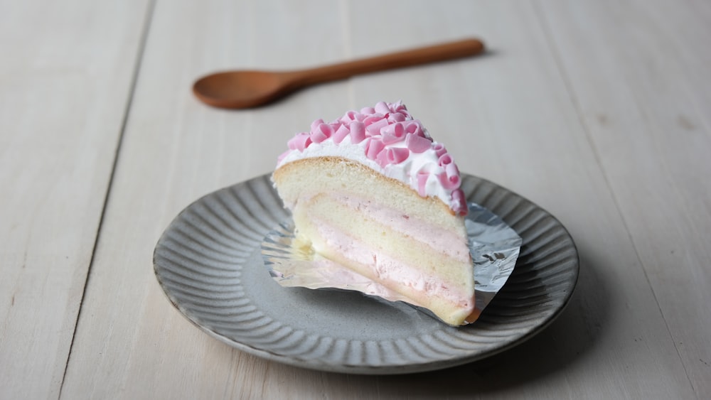 chiffon cake with white icing and pink shredded chocolate on grey plate