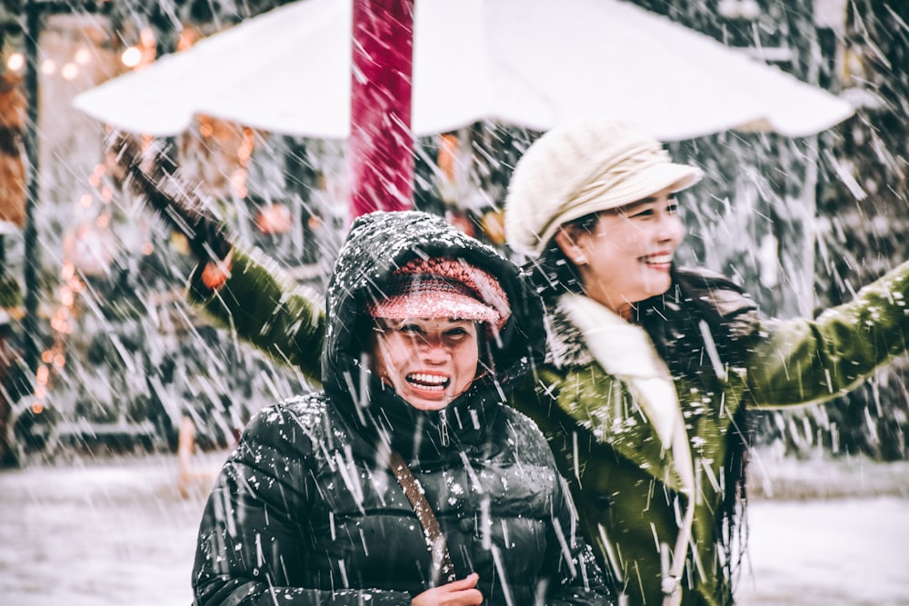 two women standing under snow storm