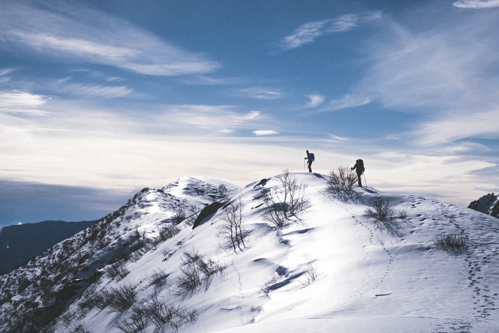 duas pessoas caminhando na montanha com neve