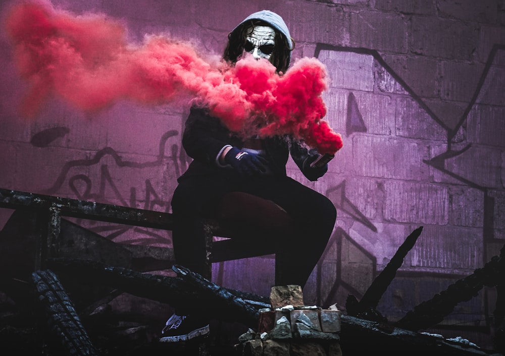 man sitting while holding red smoke signal