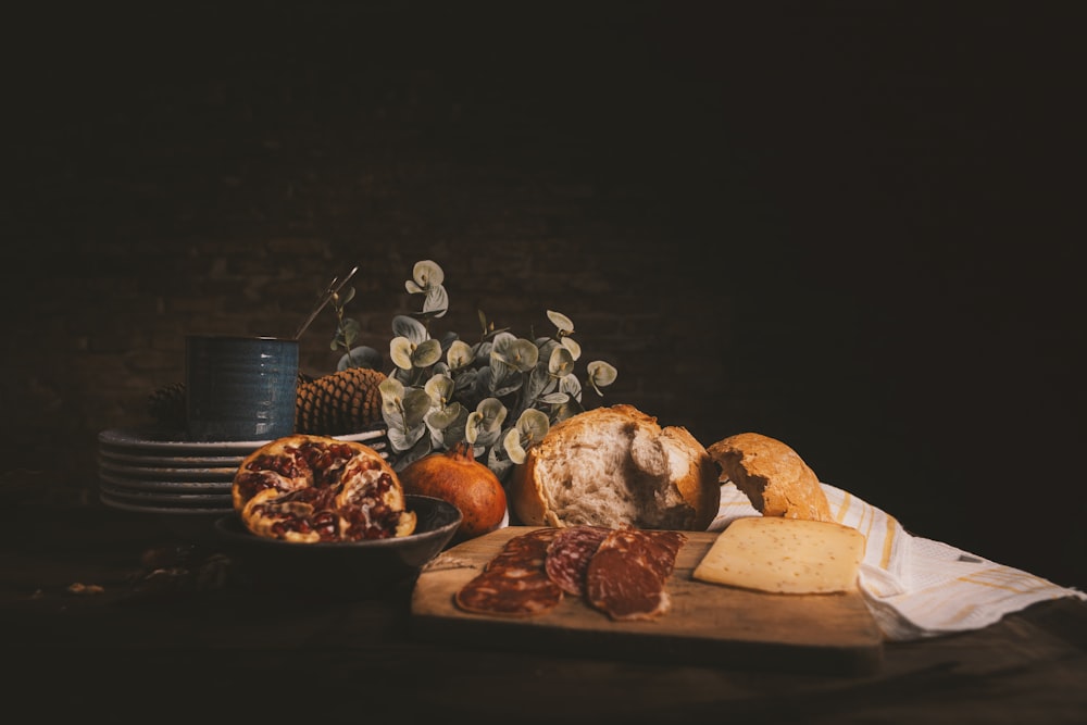 raw of meat on chopping board beside baked bread and plates on wooden table