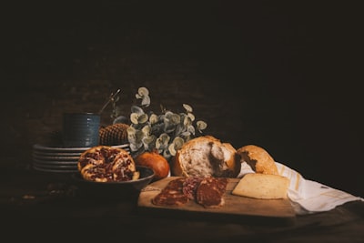 raw of meat on chopping board beside baked bread and plates on wooden table pictorial zoom background