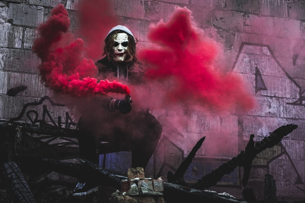 persona en cosplay de Joker sosteniendo una granada de humo