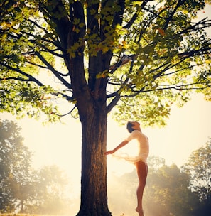 woman dancing under green tree during daytime