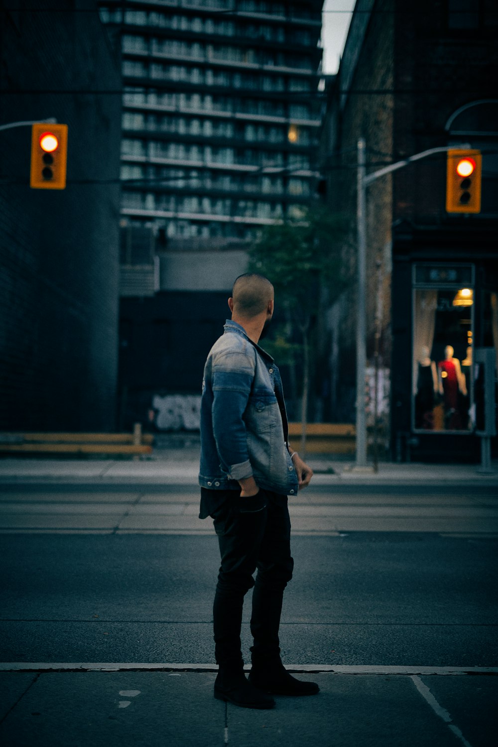 man standing near tall building and traffic lights