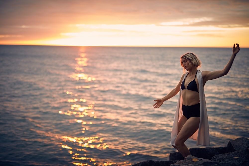 woman standing on rock formation by body of water