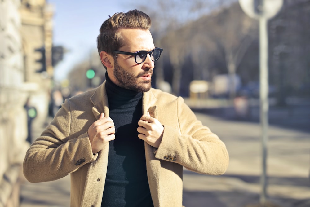 Photographie sélective de mise au point d’un homme portant un blazer brun et des lunettes