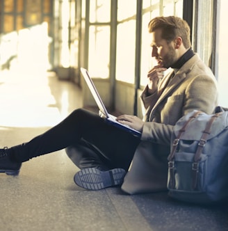 man sitting on floor while using laptop