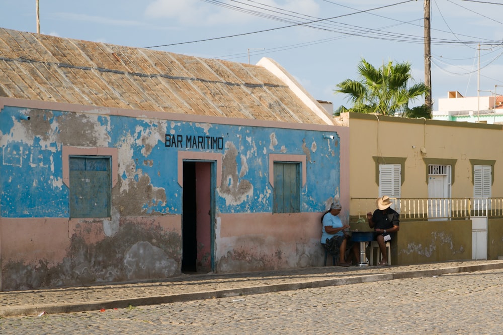 man and woman sitting outside house beside road