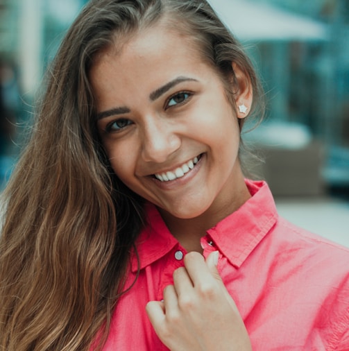 selective focus photography of woman wearing red button-up collared top while smiling