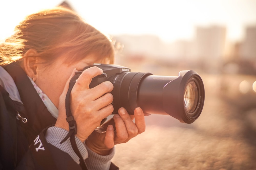 mujer usando una cámara DSLR Sony negra