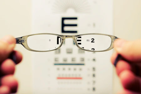 Persona sosteniendo sus anteojos por dificultad para ver de cerca