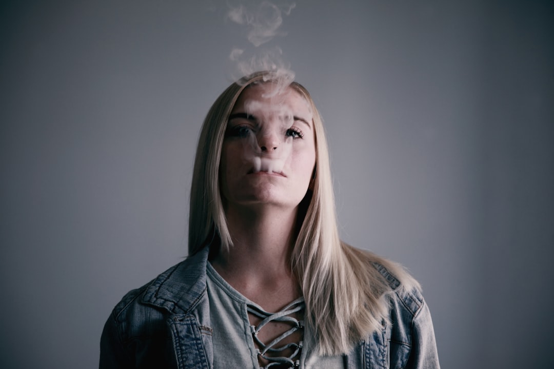 woman wears gray top smokes on mouth