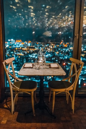 An elegant cityscape view from a rooftop dinner table under twinkling lights.