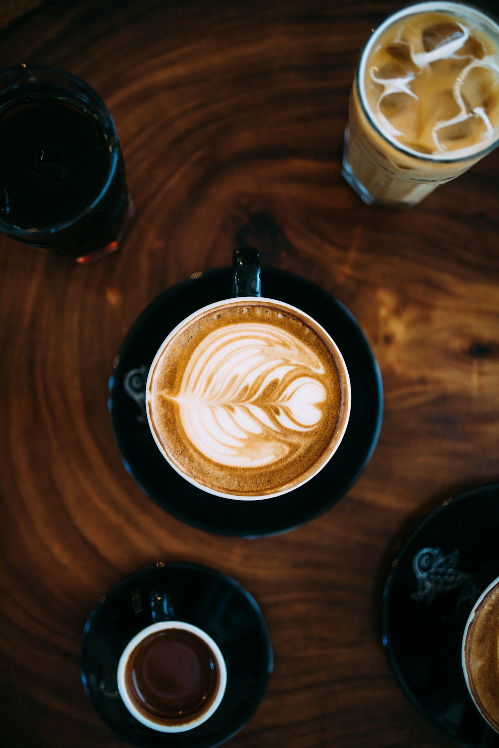 Tasse Kaffee mit aufgeschäumter Milch auf brauner Tischplatte