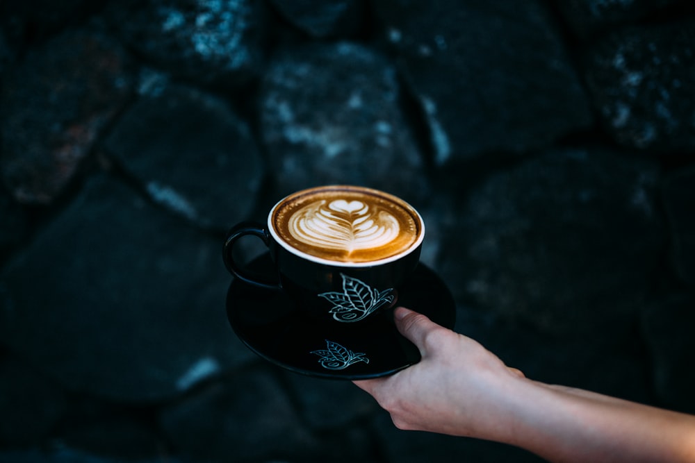 person holding teacup with cappuccino