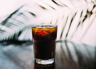 selective focus photo of glass of brown liquid