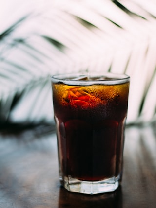 selective focus photo of glass of brown liquid