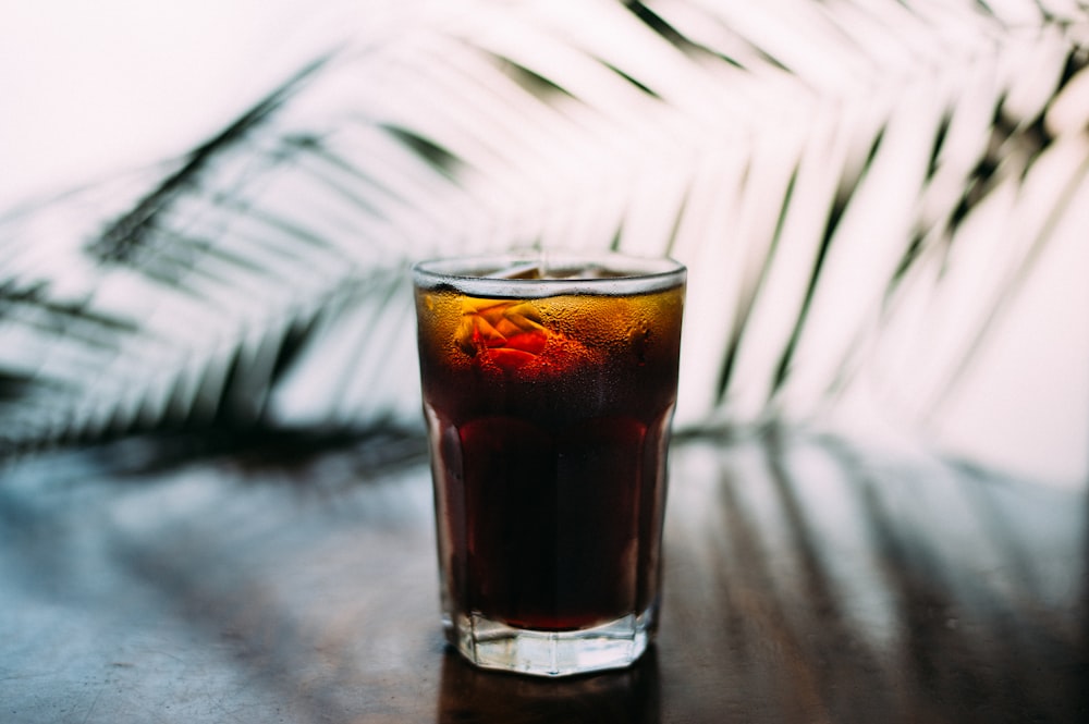 selective focus photo of glass of brown liquid