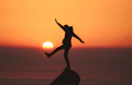 photo of silhouette photo of man standing on rock