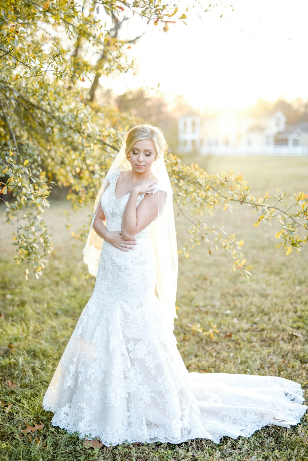 Frau trägt weißes Hochzeitskleid in der Nähe von grünem Blattbaum im Freien