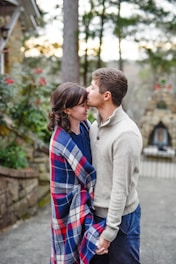 man kissing on woman forehead standing near tree during daytime