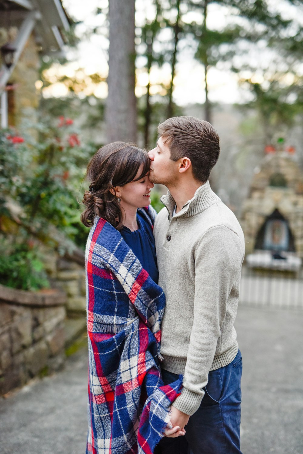 man kissing on woman forehead standing near tree during daytime